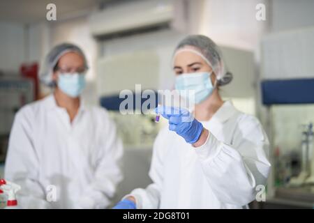 Le donne scienziati in indumenti da lavoro protettivi esaminano i campioni Foto Stock