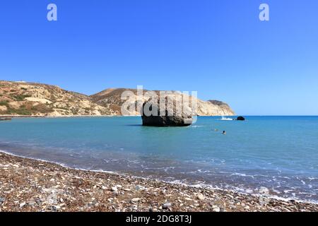 Spiaggia di Aphrodite con rocce di pietra nella baia di Aphrodite di acqua di mare mediterranea, cielo blu in background giorno di sole, Petra tu Romiou a Cipro Foto Stock