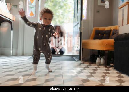 Ragazza cute del bambino in pigiama della stella che imparano camminare a. casa Foto Stock