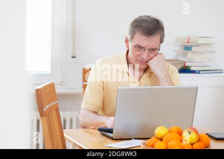 Uomo maturo stanco che lavora con il computer a casa - fuoco sulla testa Foto Stock