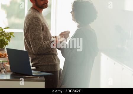Coppia che parla al computer portatile in cucina al mattino Foto Stock
