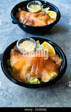 Insalata Gravlax di salmone da portare via in contenitore di plastica nera e pacchetto salsa di senape. Pronto a mangiare cibo biologico sano. Foto Stock