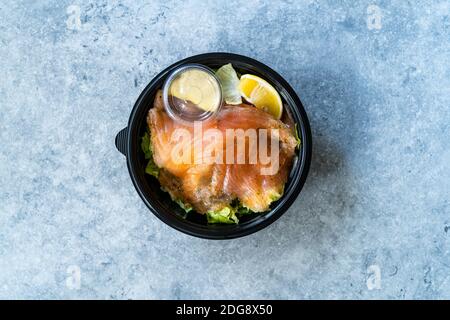 Insalata Gravlax di salmone da portare via in contenitore di plastica nera e pacchetto salsa di senape. Pronto a mangiare cibo biologico sano. Foto Stock