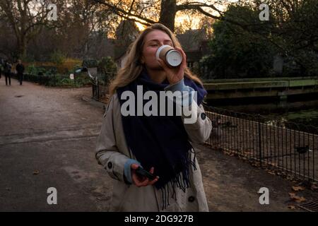 Giovane donna che beve un caffè nel parco, Westminster, Londra, Regno Unito Foto Stock