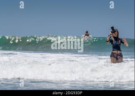 VARKALA, INDIA - Mar 14, 2020: Una fotografa femminile nelle acque che guarda la sua macchina fotografica. Foto Stock