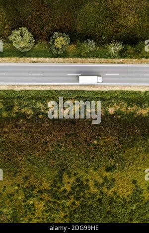 Vista aerea del camion sulla strada attraverso la campagna nel soleggiato pomeriggio estivo Foto Stock