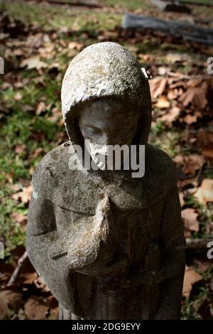 Una vignetta di una piccola figurina cementizia di San Francesco d'Assisi che tiene delicatamente un uccello Foto Stock