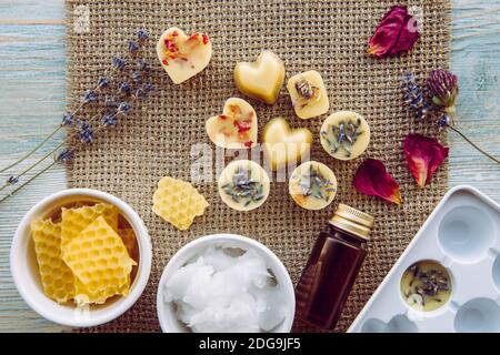 La realizzazione di mini cera fonde per diffusore di lampade aromatiche a casa concetto. Strumenti ingredienti sulla tavola cera d'api greggi, olio di cocco solido, olio essenziale. Foto Stock