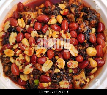 arachidi fritte fresche nell'olio speziato rosso nel recipiente bianco Foto Stock