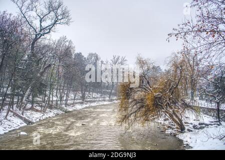 L'acqua sporca del fiume passer dopo una nevicata pesante e la sua passeggiata ai lati di Merano, Italia coperta di neve bagnata. Foto Stock