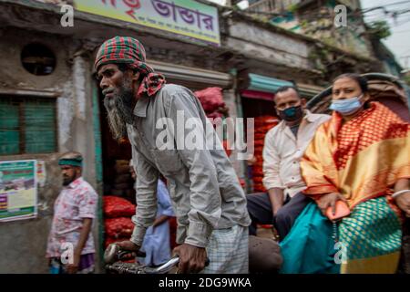 Pulitori di risciò per le strade di Puran Dhaka - Old Dhaka in Bangladesh. I risciò sono tricicli alimentati a pedale, ma usati per essere tirati a mano, da qui 'estrattore di risciò'. Oggi molti dei risciò sono persino convertiti per essere alimentati da un motore elettrico. Foto Stock