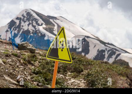 Russia. Regione di Krasnodar. Un cartello che avverte i turisti del pericolo di cadere da una scogliera in montagna. Foto Stock