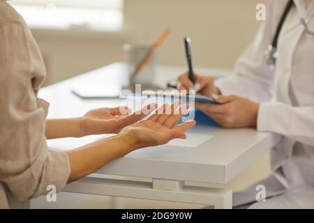 Primo piano delle mani del medico e del paziente che discute di diagnosi seduto in ospedale Foto Stock