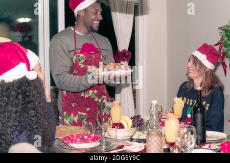 Buon Natale! Buona famiglia sta cenando a casa. Grande famiglia multigenerata e multietnica che si diverte con la cena di natale. Famiglia, Foto Stock