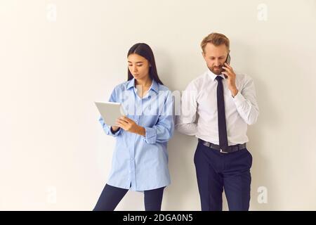 Due colleghi che usano i gadget durante la pausa al lavoro ignorando completamente l'uno con l'altro Foto Stock