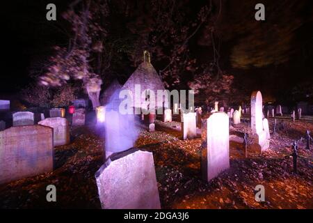 Auld Kirk, Alloway , Sud Ayrshire, Scozia, Regno Unito. Cimitero illuminato per Halloween. Figura annodata offuscata in amonst le tombe parte invisibile Foto Stock