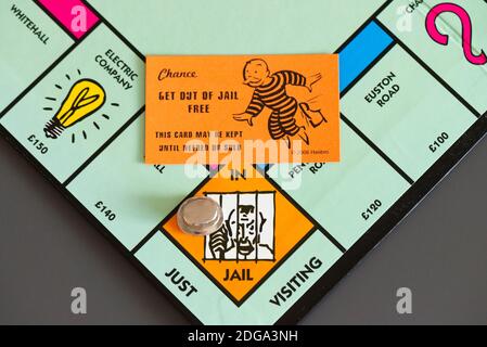 Una Chance uscire di Jail carta libera su un Monopolista bordo accanto alla parte superiore cappello da gioco su La piazza in Gaol/Just Visiting Foto Stock