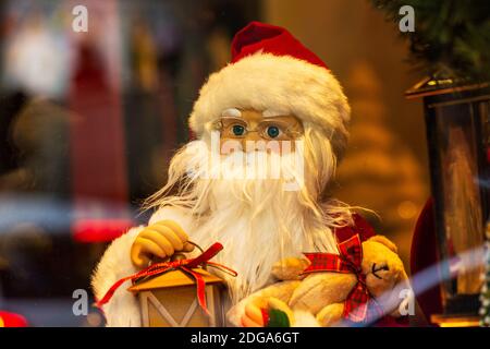 Bambola di Natale del padre con gli occhiali ed il cappello rosso che tiene la lanterna della candela in luce calda. Foto Stock