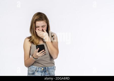 Bella bionda Teenage modello avendo divertimento con il suo telefono dentro Un ambiente Studio Foto Stock