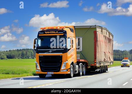 Giallo Volvo FH Truck semirimorchio Rantala trasporta la cabina portatile come carico di grandi dimensioni, segue il veicolo di scorta. Jokioinen, Finlandia. 15 giugno 2020. Foto Stock