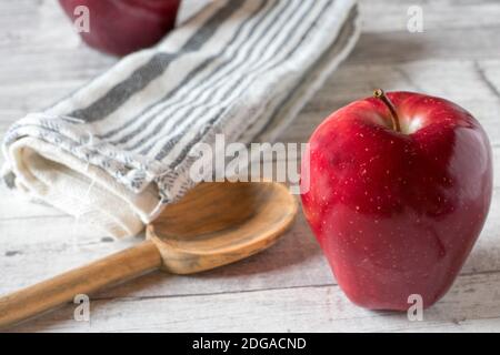 Mela rossa su un tavolo da cucina con cucchiaio di legno Foto Stock