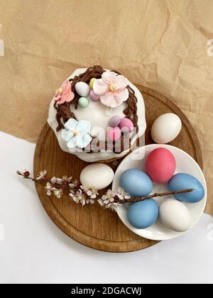 Uova di pasqua colorate e sfondo torta di pasqua su scrivania di legno Foto Stock