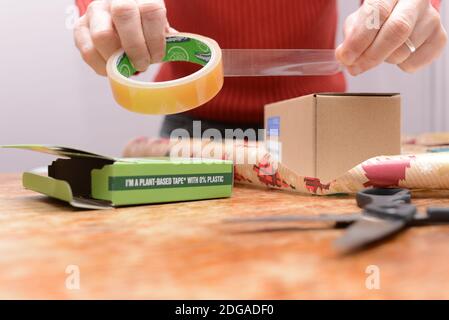 Utilizzo di un nastro Sellotape in plastica zero. Un esempio di un prodotto ridisegnato, utilizzando cellulosa e colla naturale, per essere più sostenibile ed ecocompatibile. Foto Stock