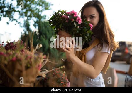 felice giovane donna caucasica sceglie fiori in vaso per acquistare a. giardino all'aperto Foto Stock