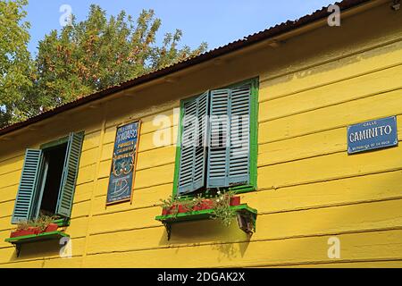 Facciata gialla vivida con finestre in legno blu e verde la luce solare Foto Stock