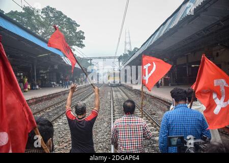 Kolkata, India. 8 dicembre 2020. I sostenitori del partito comunista hanno bandiere mentre bloccano la via ferroviaria durante la dimostrazione. Lo sciopero All India chiamato dai sindacati dei contadini contro le nuove leggi sull'agricoltura è sostenuto dai partiti di opposizione. Credit: SOPA Images Limited/Alamy Live News Foto Stock