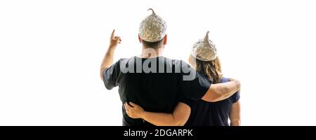 Un uomo guarda al futuro con sua moglie, entrambi indossando cappelli in alluminio. Foto Stock