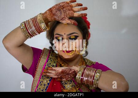 una bella ragazza indiana in abito da sposa con saree rosse e ornamenti d'oro che mostrano il tatuaggio chiamato mehindi Foto Stock