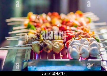 Frutti di mare e barbecue di manzo (BBQ) spiedati su bastoncini di bambù con torta di mela, pomodoro, cipolla e peperoncino sono grigliate sul piano cottura per barbecue festa. Barbec Foto Stock