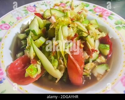 Insalata di cetrioli piccante, cibo tailandese di strada con pomodoro e peperoncino sul piatto. Questa insalata piccante di cetrioli tailandese ha un classico sapore asiatico, con un tocco di sudore Foto Stock