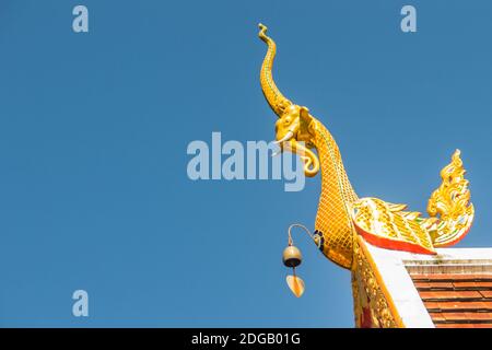 Belle sculture dorate di naga sul tetto della chiesa sotto lo sfondo blu del cielo a Wat Phra che Doi Tung, uno dei quali si ritiene contenere l Foto Stock