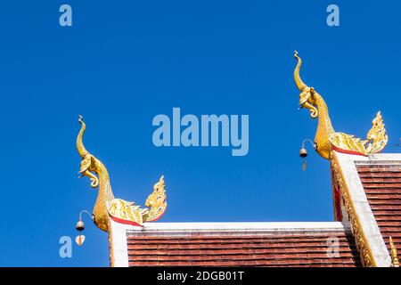 Belle sculture dorate di naga sul tetto della chiesa sotto lo sfondo blu del cielo a Wat Phra che Doi Tung, uno dei quali si ritiene contenere l Foto Stock
