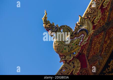 Belle sculture dorate di naga sul tetto della chiesa sotto lo sfondo blu del cielo a Wat Phra che Doi Tung, uno dei quali si ritiene contenere l Foto Stock