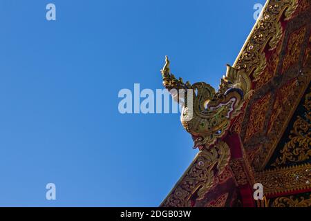 Belle sculture dorate di naga sul tetto della chiesa sotto lo sfondo blu del cielo a Wat Phra che Doi Tung, uno dei quali si ritiene contenere l Foto Stock