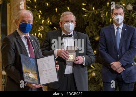 08 dicembre 2020, Baviera, Monaco di Baviera: Reinhard Genzel (M), fisico tedesco, detiene la medaglia d'oro nelle mani quando riceve il Premio Nobel per la fisica. A sinistra si trova per Thöresson, ambasciatore svedese in Germania, con il certificato, e a destra si trova Markus Söder (CSU), primo ministro della Baviera. A causa della pandemia di Corona, i vincitori riceveranno medaglie e certificati non a Stoccolma, ma in luoghi diversi. Foto: Peter Kneffel/dpa Foto Stock