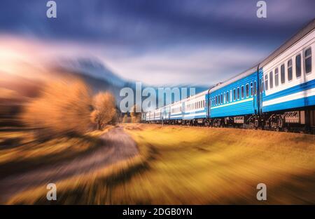 Treno in movimento in montagna al tramonto con effetto di sfocatura del movimento Foto Stock