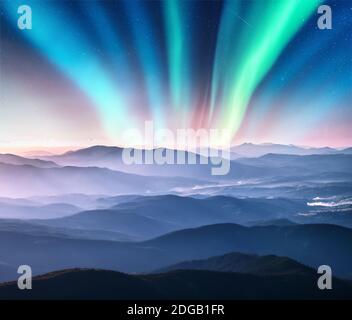 Aurora borealis sopra la valle di montagna in basse nuvole a. notte Foto Stock