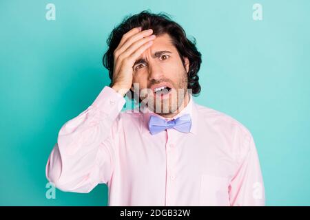Ritratto fotografico dell'uomo preoccupato che tiene la testa con la mano isolata su sfondo color teal pastello Foto Stock