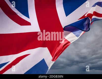 EU Brexit Concept UK Union Jack Flag volare con la brezza soffiare attraverso il svelare il cielo scuro dietro come metafora per i problemi e il concetto per le frontiere del Regno Unito Brexit immigrazione negoziati di pesca ecc.... Foto Stock