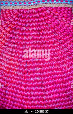 Motivo intrecciato rosa sulla borsa donna. Borsetta in rattan naturale, di colore rosa, realizzata a mano per lo sfondo. Foto Stock