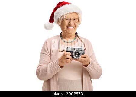 Signora anziana con una macchina fotografica vintage che indossa un babbo natale cappello isolato su sfondo bianco Foto Stock