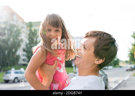 felice famiglia, ragazza, figlia di 5-6 anni, allegro e gioioso uomo, padre, educazione da genitore, emozioni di felicità, gioia gioia, si alza dentro Foto Stock