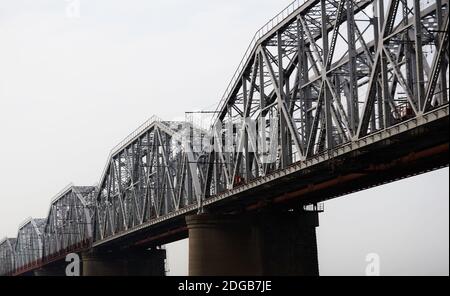 vista dal basso verso l'alto di diverse stese di una truss ferroviaria ponte contro un cielo nuvoloso Foto Stock