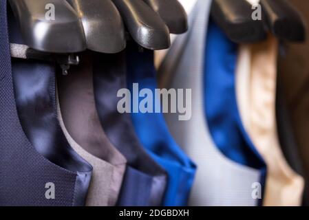 Elegante giubbotto da uomo da primo piano. svest maschile appeso in una fila. Abbigliamento uomo, shopping in boutique, gilet e tute in un lusso maschile Foto Stock