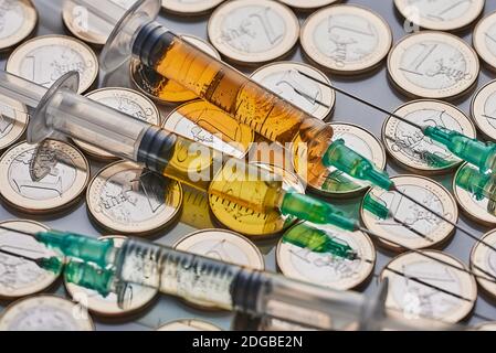 siringhe su una montagna di soldi. vaccino covid Foto Stock