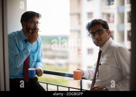 Incontri aziendali con caffè/tè e sigaretta tra giovani ed energici Dirigenti/funzionari/dirigenti indiani bengalesi sul balcone dell'edificio degli uffici Foto Stock